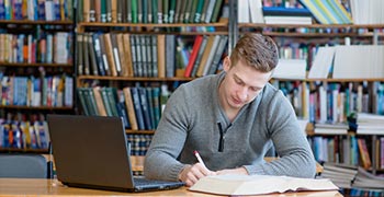 Student reading and using laptop to study