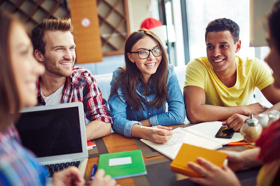 A group of smiling students studying at a table